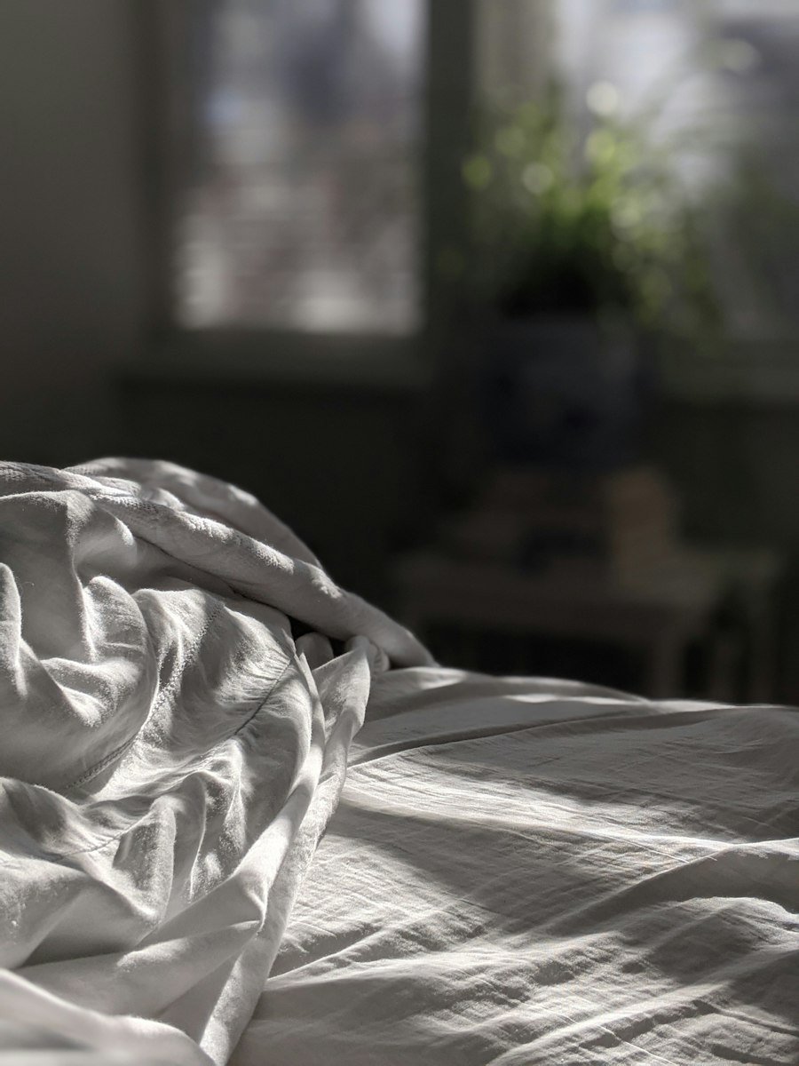 Mattress with white cover on a wooden bed